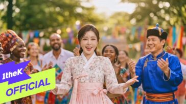 Cantora Song Ga In sorri e dança em meio a um grupo diverso, celebrando em um ambiente festivo ao ar livre.