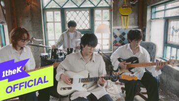 Quatro músicos tocam instrumentos em um ambiente aconchegante, com janelas grandes e decoração colorida.