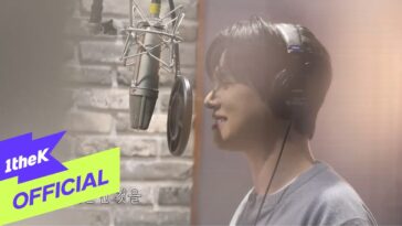 Chu Hyuk Jin sorrindo enquanto grava no estúdio, com microfone e fones de ouvido.