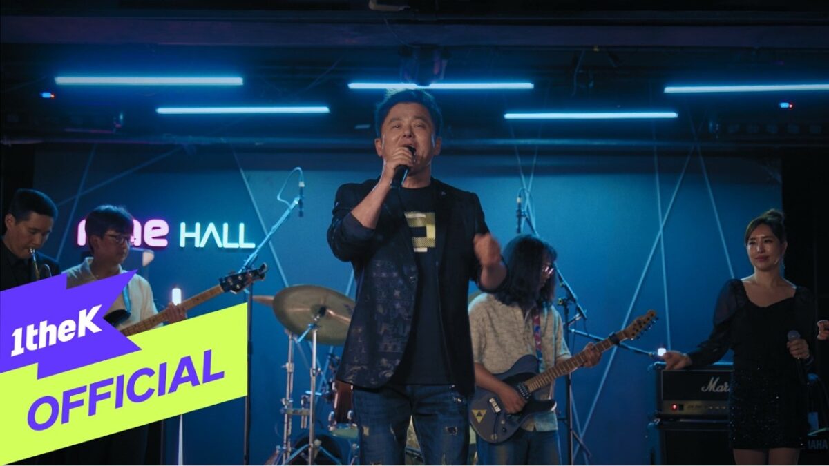 Goo Chang Mo se apresenta ao lado da banda em um palco iluminado, transmitindo emoção durante o reencontro musical.