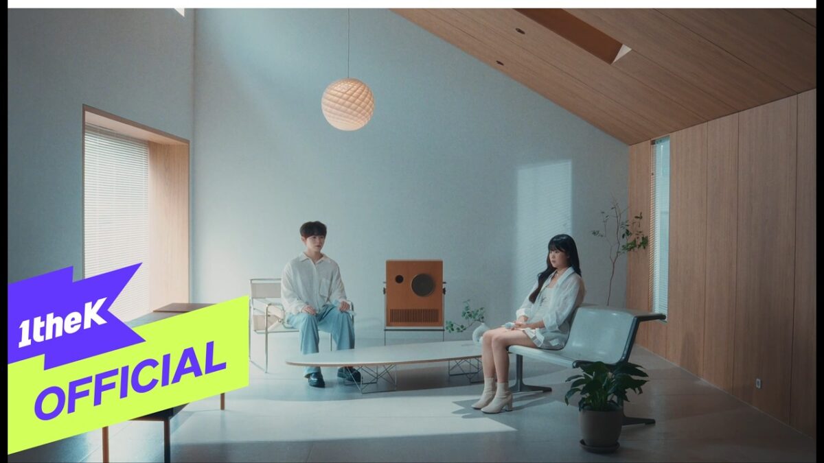 Dois jovens sentados em um ambiente minimalista, com móveis modernos e iluminação suave.