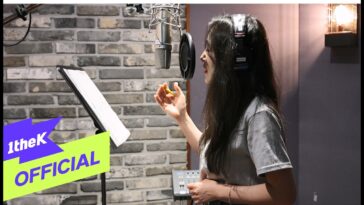 Chae Yoon canta em estúdio, usando fones de ouvido e segurando uma caneta, com partitura à sua frente.