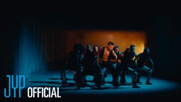 Park Jin-young e dançarinos em uma coreografia intensa, iluminados por luzes dramáticas em ambiente escuro.