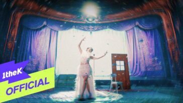 Artista em vestido esvoaçante dança em palco decorado, com cortinas roxas e uma porta ao fundo. Pétalas caem ao redor.
