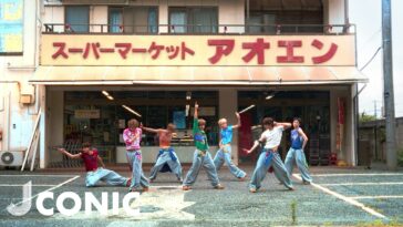 Grupo de dançarinos se apresentando em frente a um supermercado, com roupas coloridas e coreografia animada.